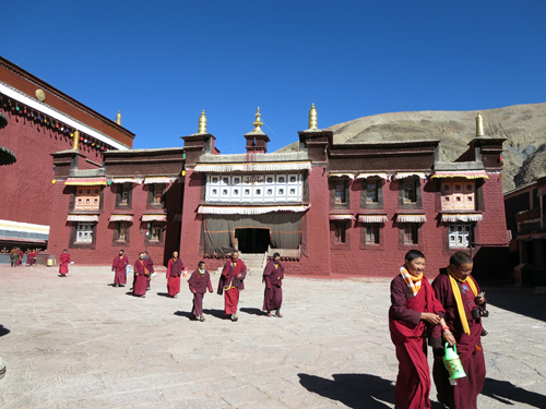 Buddhist monks walk the courtyard of Jokhang Temple