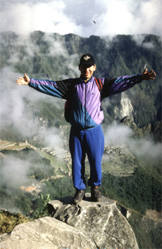 A Peruvian guide stands on a rock overlooking Machu Picchu.